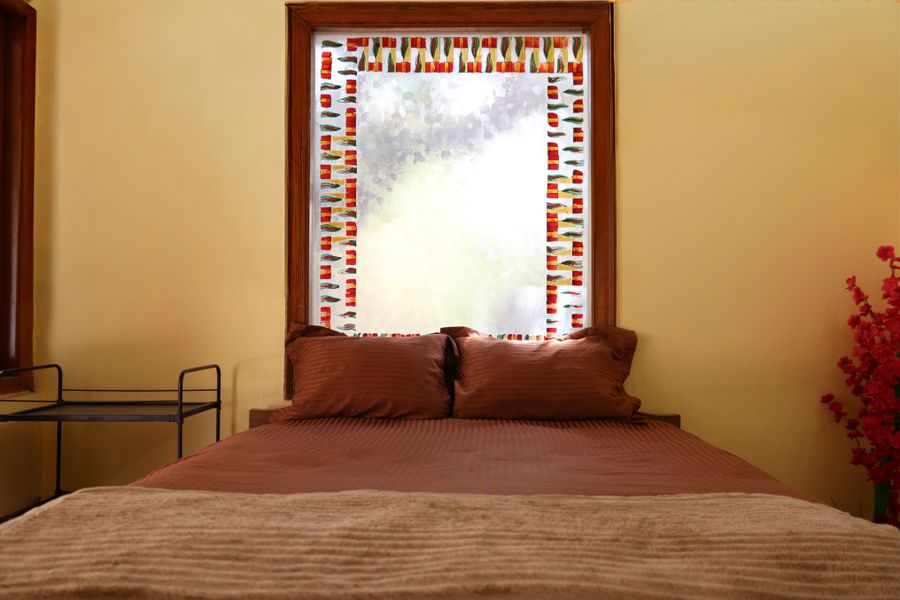 A warm bedroom with a decorative window and brown bedding, Ahmedabad