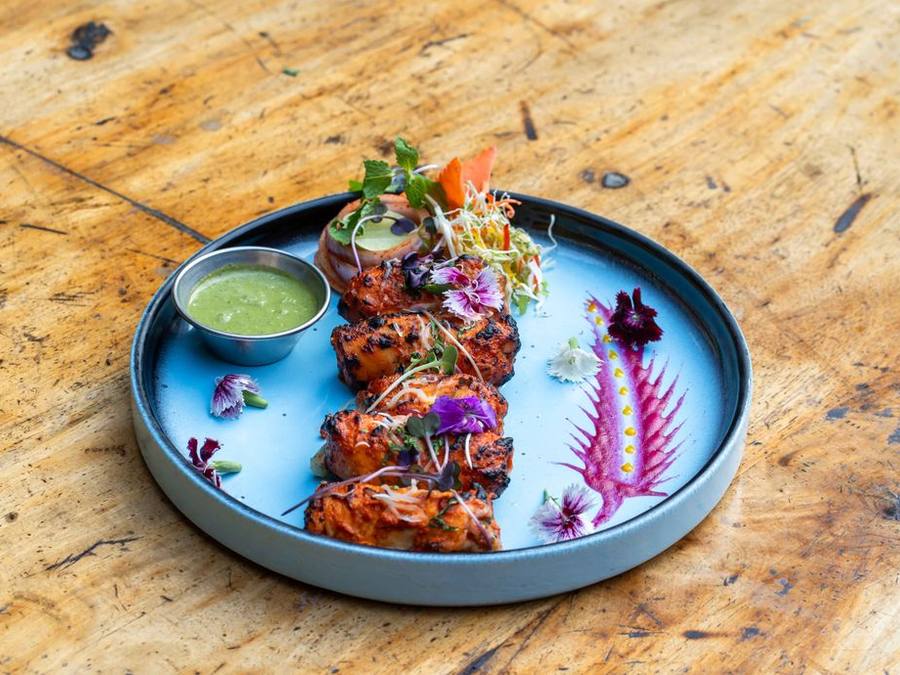 Fine-dining plated tandoori dish on a blue plate on a wooden table