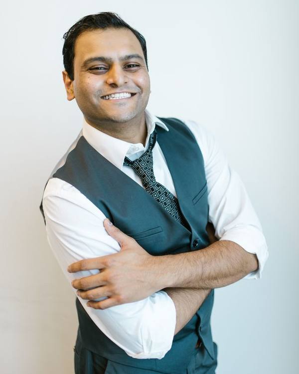 Smiling Indian man in a waistcoat with arms crossed