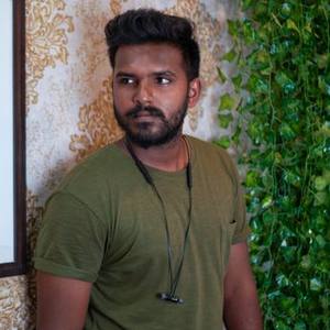 Indian man in a green t-shirt standing against a wall