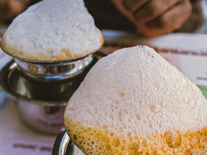 Filter coffee being frothed between two steel tumblers