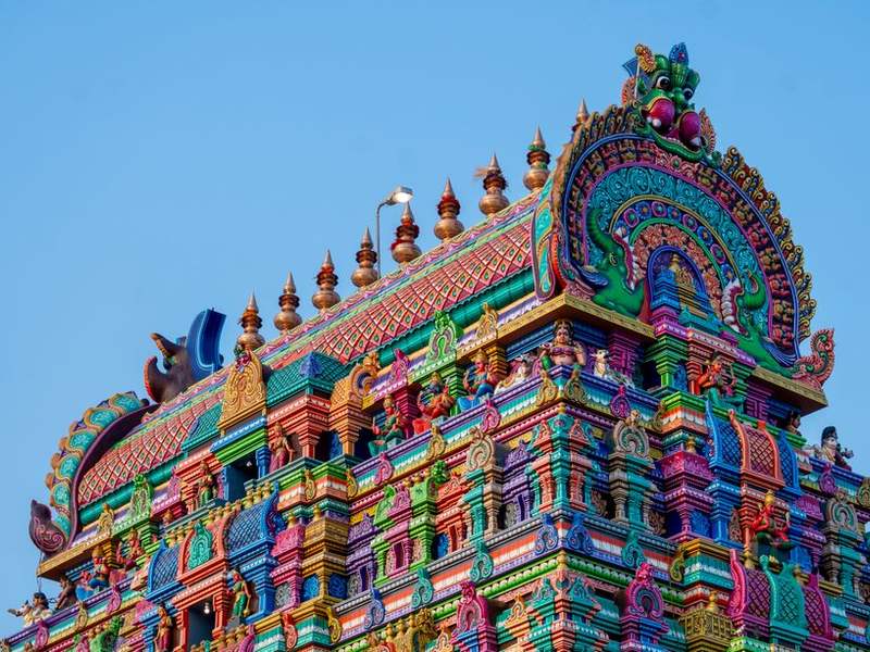 Brightly painted gopuram tower of a South Indian temple against a blue sky