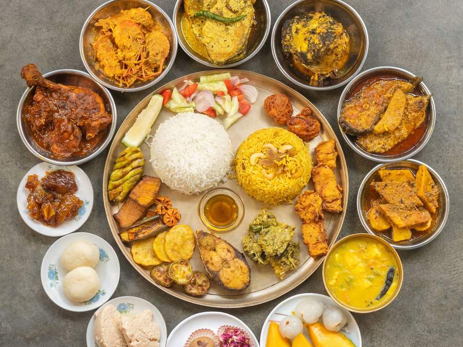 Overhead view of a festive vegetarian thali with many small bowls of curries and sweets