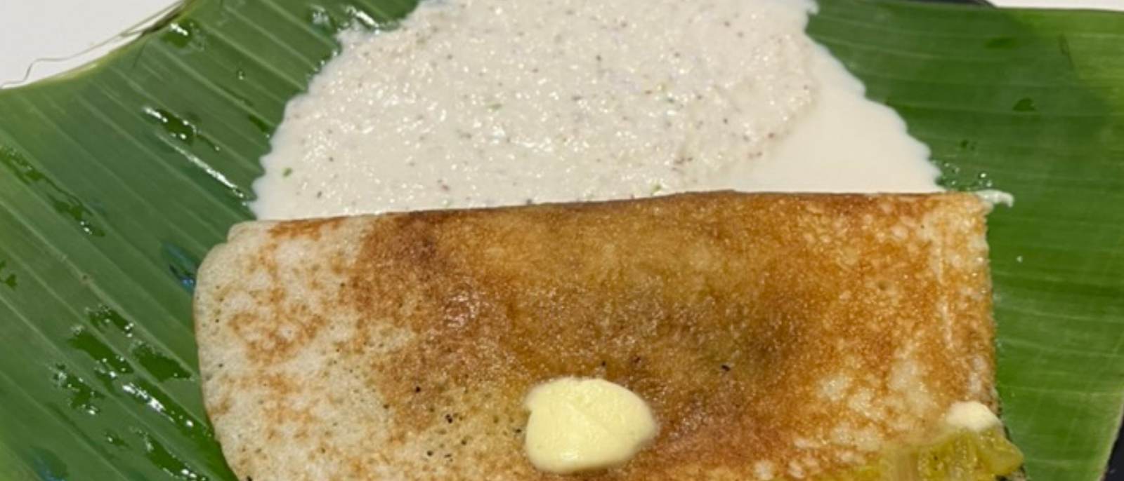 Crisp masala dosa served on a banana leaf with sambar and chutneys