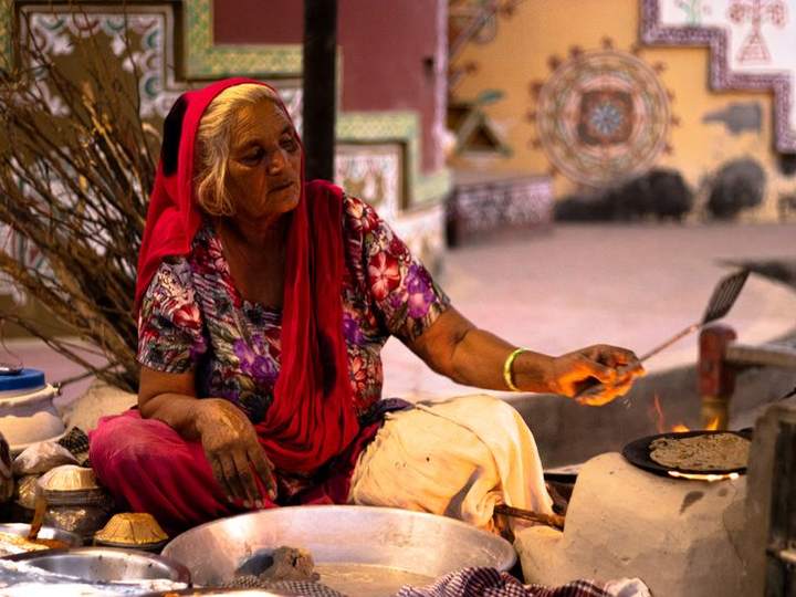 An Indian woman rolling rotis in a traditional kitchen