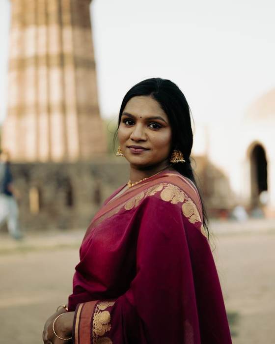 Smiling Indian woman in a maroon saree standing outdoors