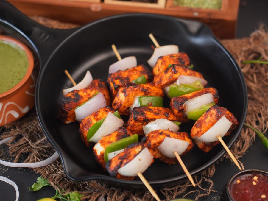 Char-grilled paneer tikka skewers with peppers and onions fresh off the sigri