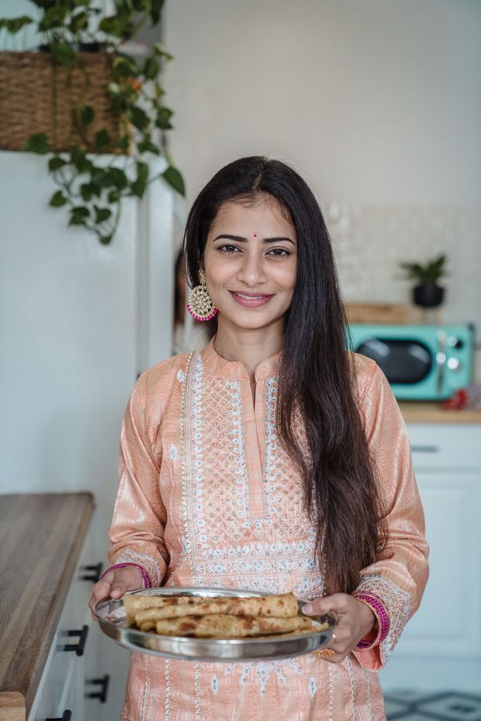 Shirin Bano in traditional attire presenting a tray from the mithai studio