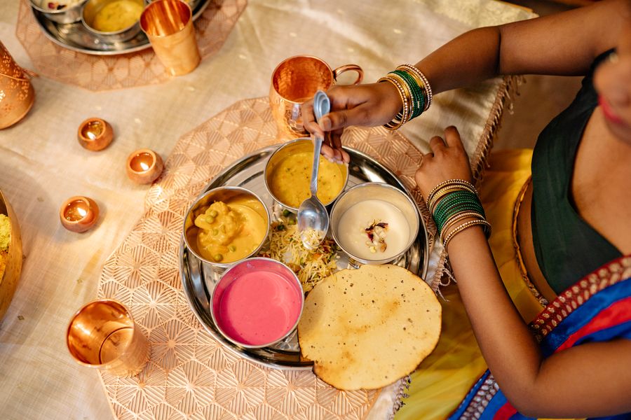 A vibrant festive thali being served at an Indian wedding celebration with diyas