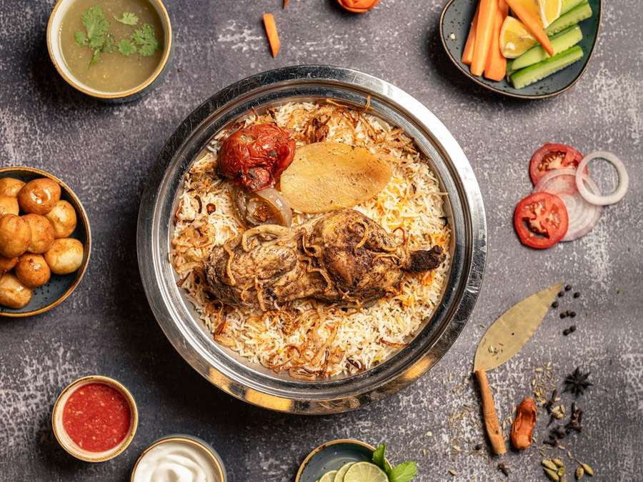 Overhead view of a biryani thaal spread with bowls of curry, salad and chutneys