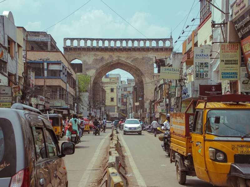 Busy old-city street in Hyderabad leading to a stone gateway
