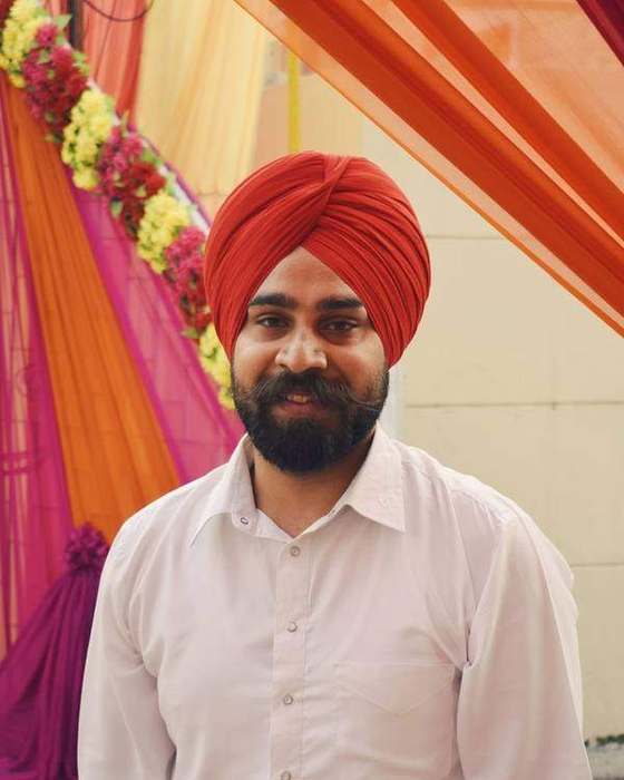 Smiling Sikh man in a red turban and white kurta