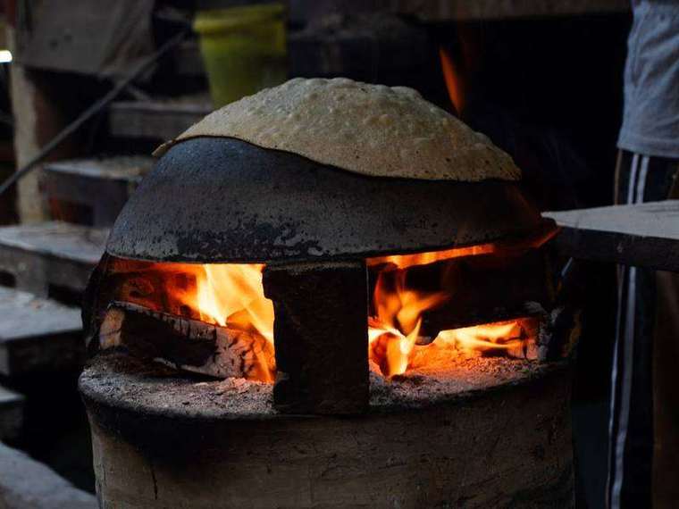 Roti puffing over the fire of a clay tandoor