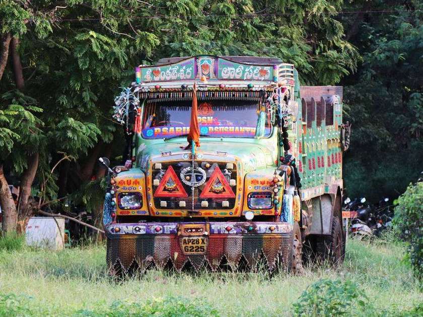 Colourfully painted Indian truck parked beside trees