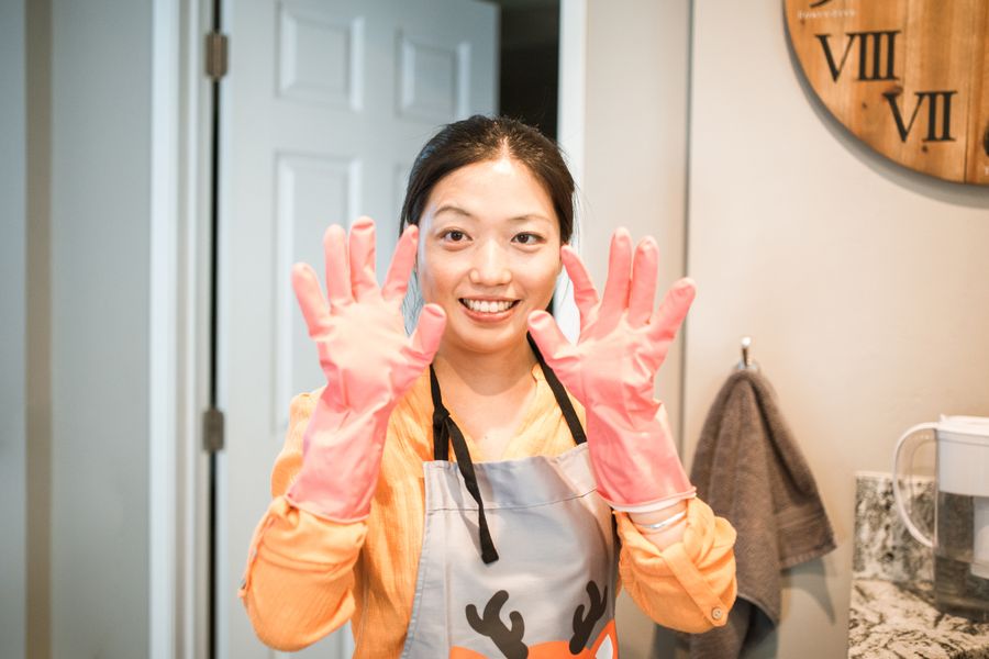 A smiling cleaning professional in apron and gloves in a finished kitchen