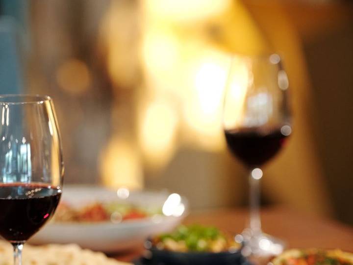 Glasses of red wine on a table at a candle-lit dinner