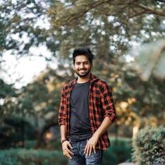 Indian man in a checked shirt smiling outdoors
