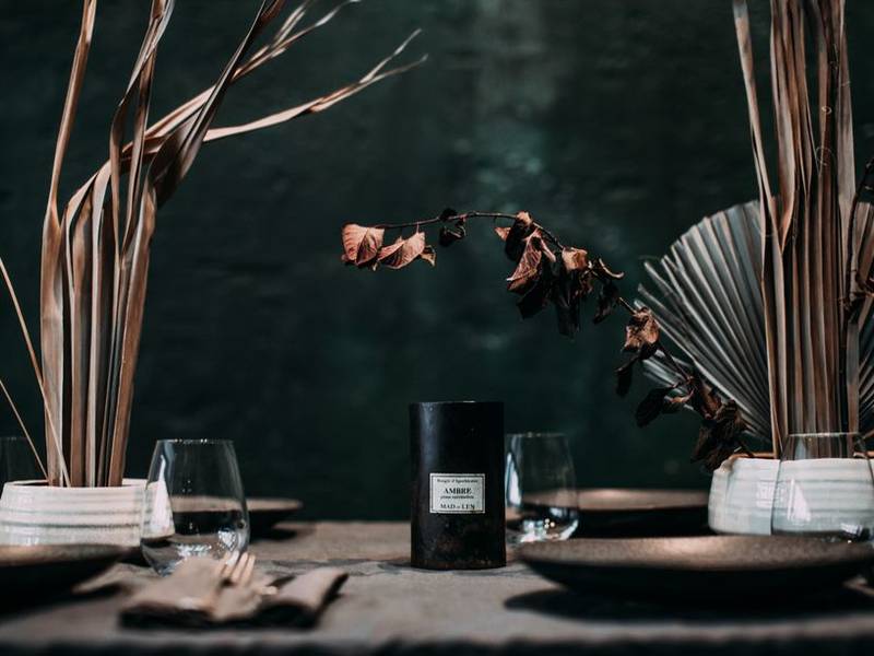 A dark elegant dining room with a long table set with wine glasses