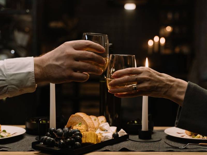 Glasses of red wine being poured at a candle-lit dinner table