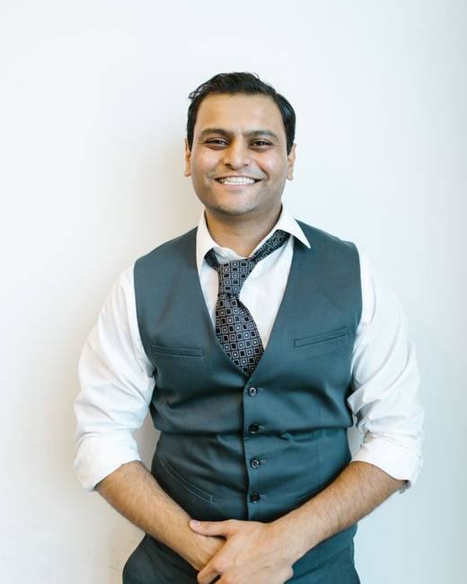 Indian man in a waistcoat and tie, smiling