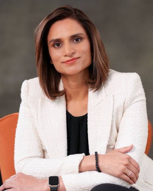 Smiling Indian woman in a white jacket, arms folded