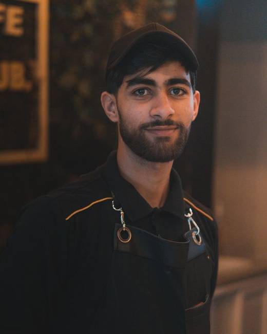 Bearded Indian man in a dark shirt photographed against a dark background
