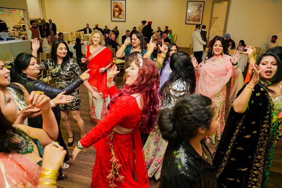 Women dancing joyfully at a festive Indian celebration indoors