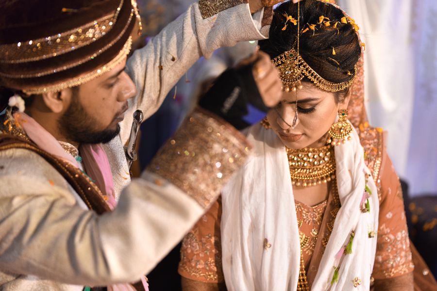 A bride and groom exchanging rituals at a traditional Indian wedding ceremony
