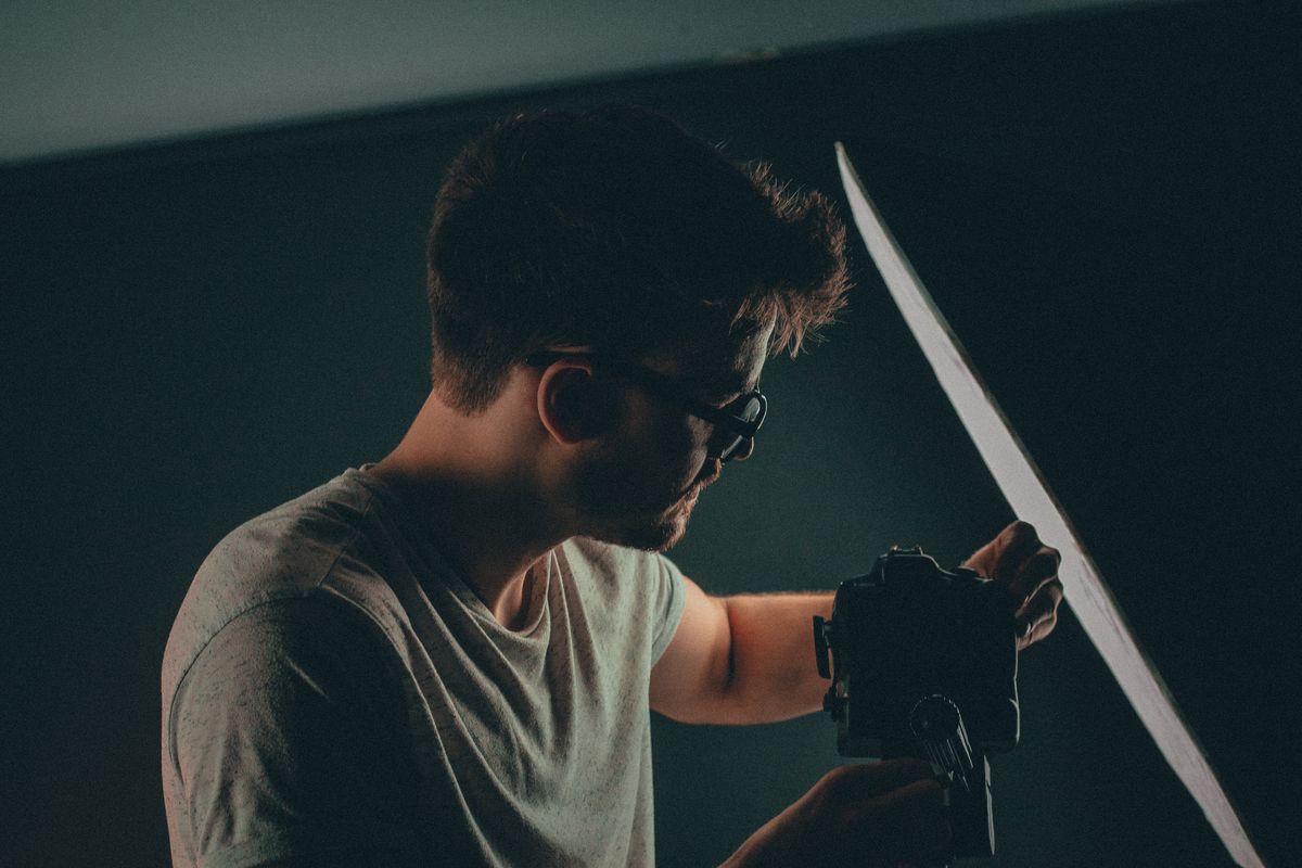 A photographer adjusting his camera amid studio lighting in a low-lit set