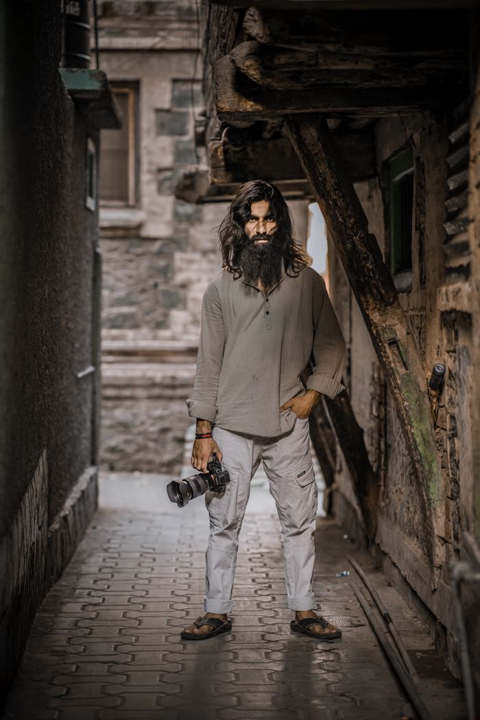 Aditya Rathore, Founder and Lead Photographer, holding his camera in an old city alley