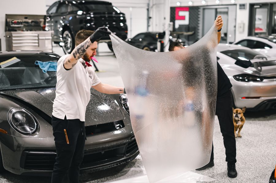 Two installers applying protection film to a luxury car in the studio