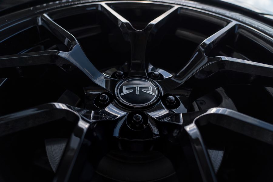 A freshly detailed black alloy wheel with mirror reflections