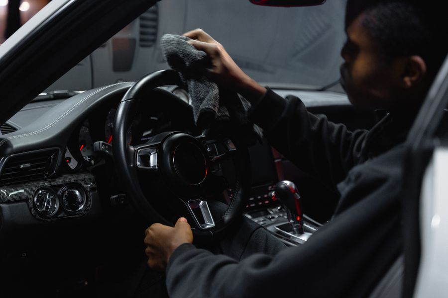 A technician wiping down a steering wheel during an interior deep-clean