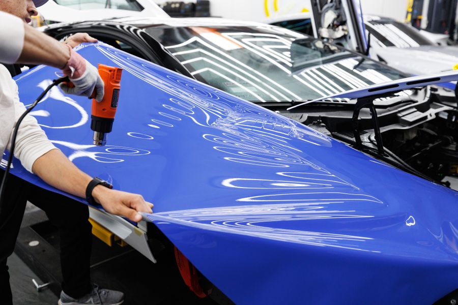 An installer heat-forming protection film onto a car panel
