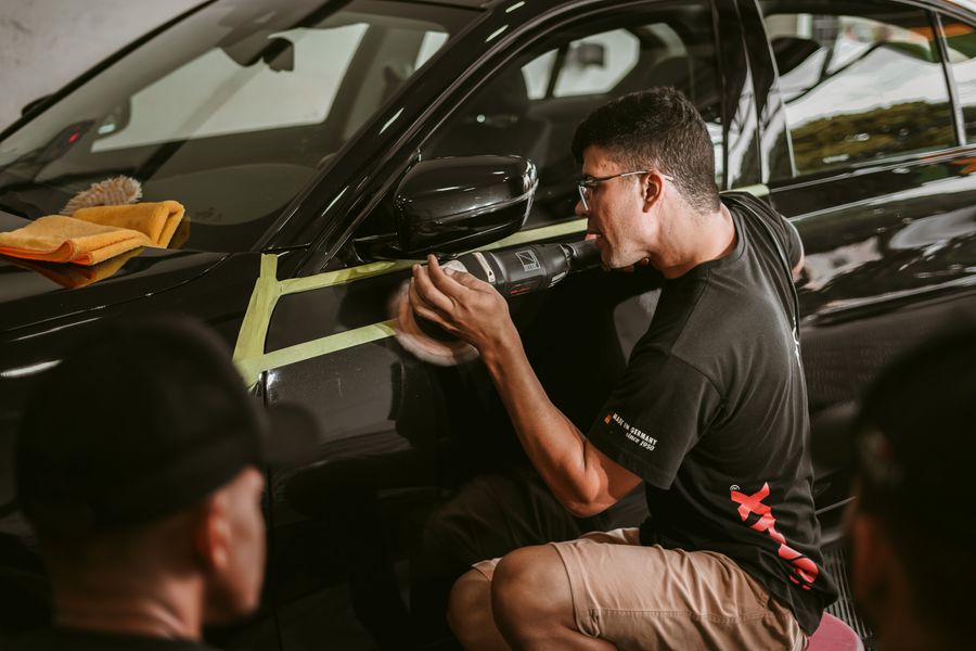 A detailer machine-polishing a car bonnet in the correction bay
