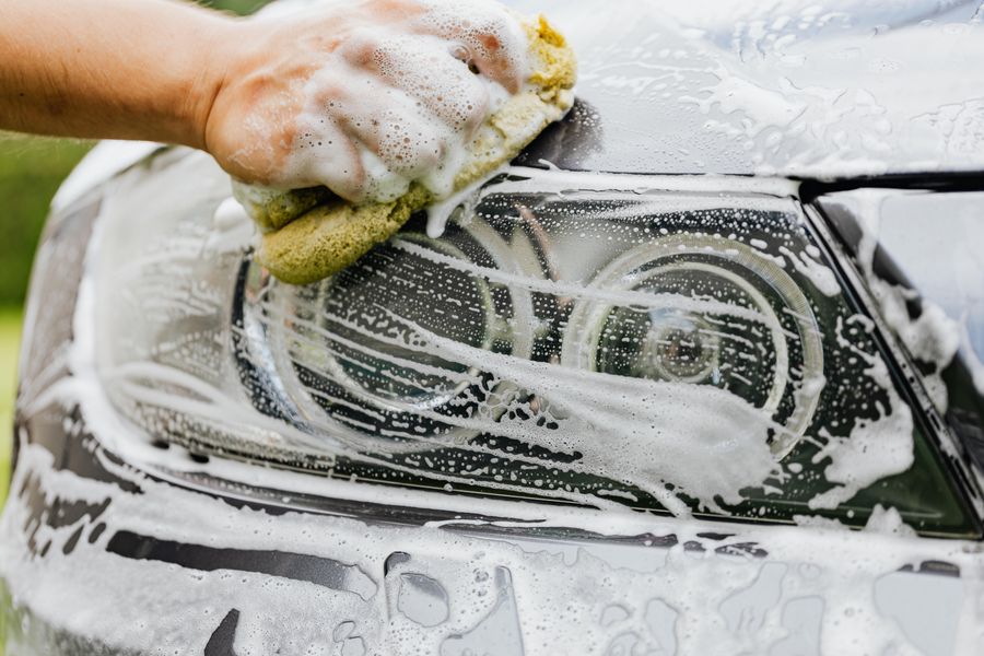 A headlight being scrubbed and restored during detailing