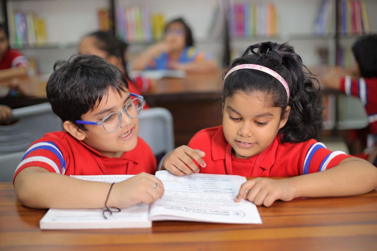 Two young children reading a picture book together in a bright Gubbara classroom