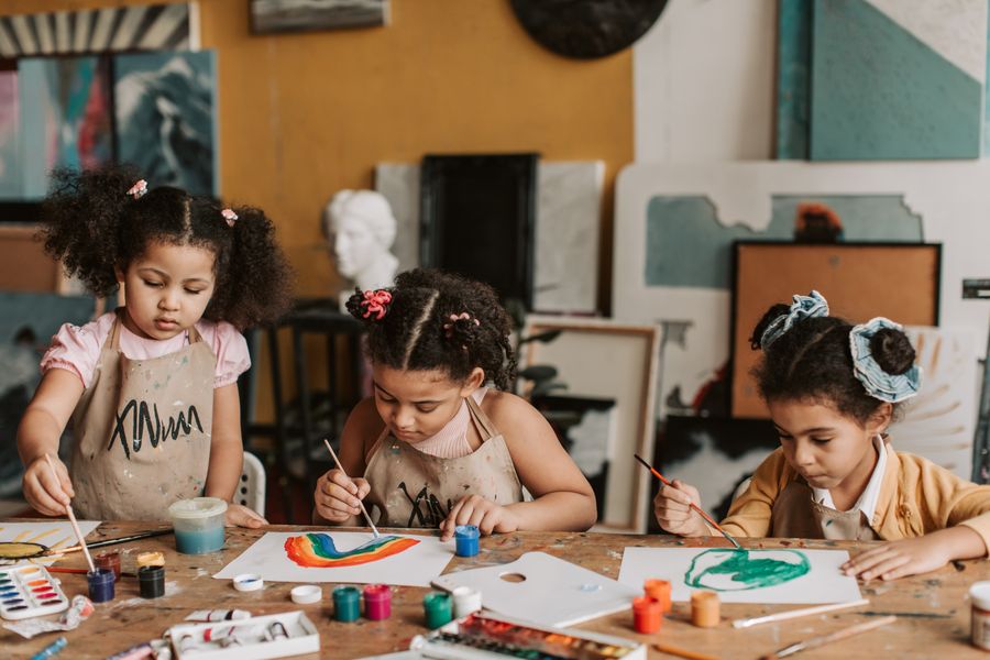 Three children painting at a table during an art and craft session