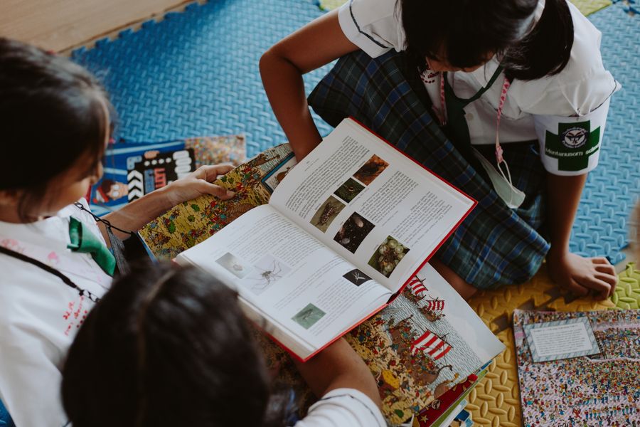 Three children reading storybooks together at the Gubbara reading corner