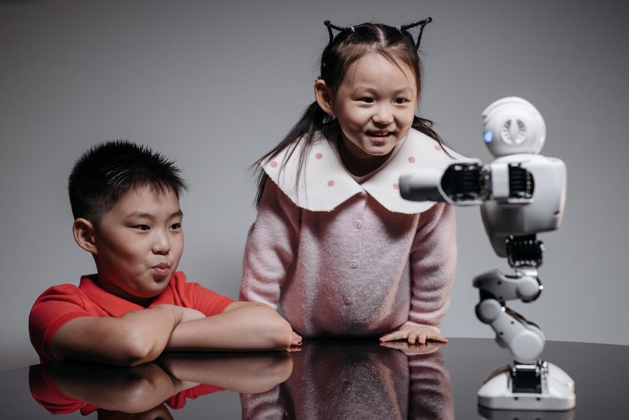Two children playing with a small educational robot in the STEM lab