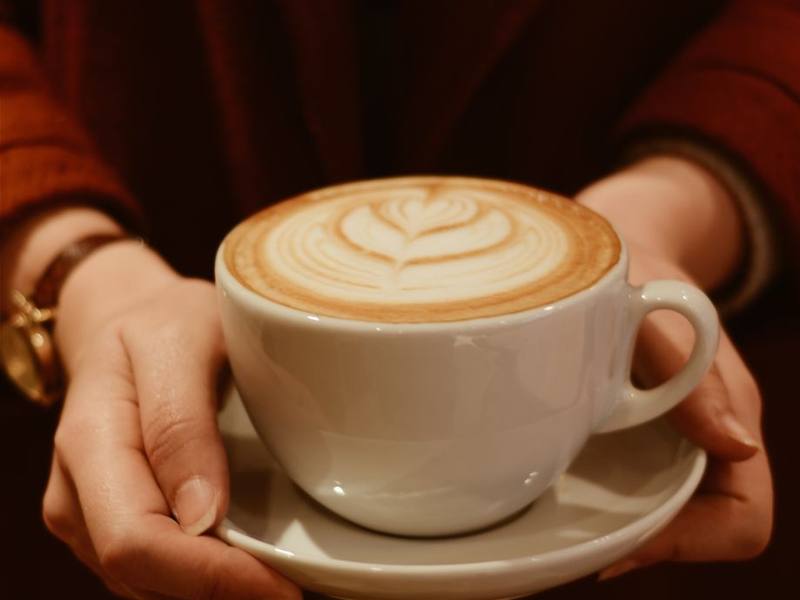 Hands cupping a latte with leaf art