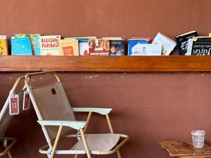 Person browsing tall bookshelves in a café corner