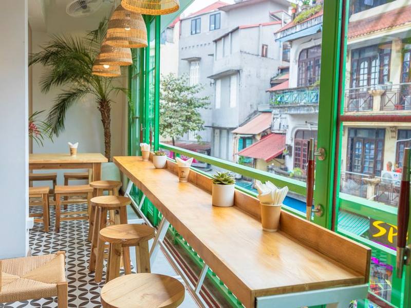 Bright café window seat with green frames and plants looking onto the street