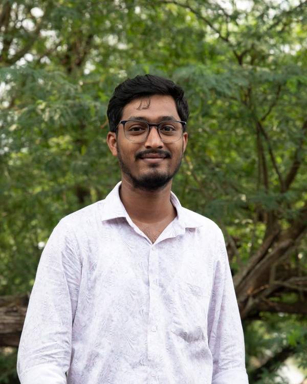 Young Indian man in a white shirt smiling outdoors