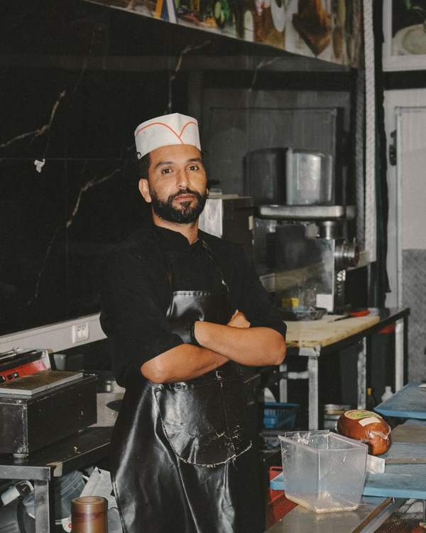 Indian chef in a white cap and apron standing in a restaurant kitchen