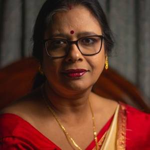 Indian woman with glasses in a red saree, smiling