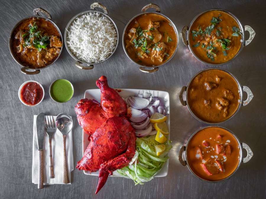 Overhead view of a thali with crab, rice and several curries