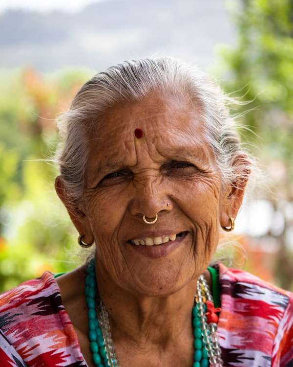 Elderly Indian woman with a nose ring smiling warmly outdoors