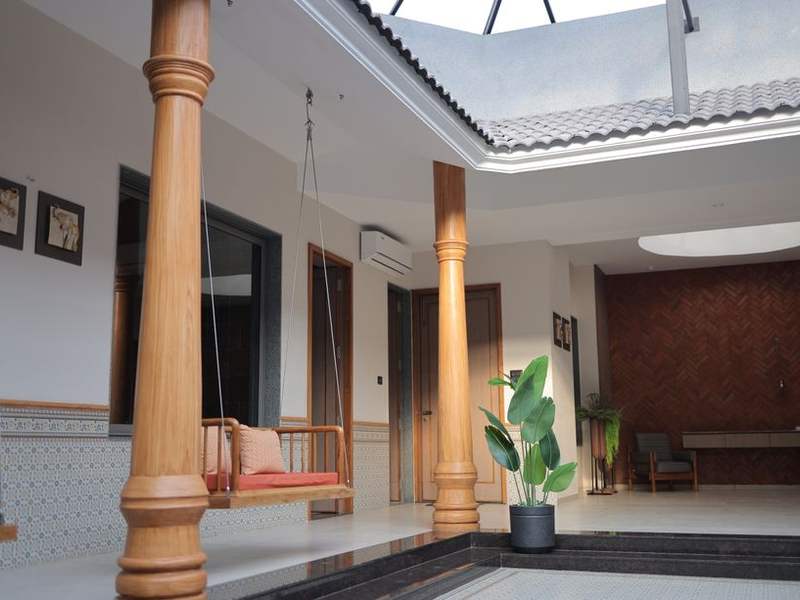 Bright courtyard of a Chettinad house with wooden pillars and a swing
