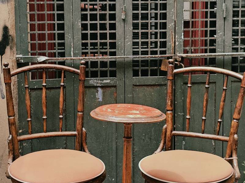 Bentwood chairs and a small table by tall green-framed windows
